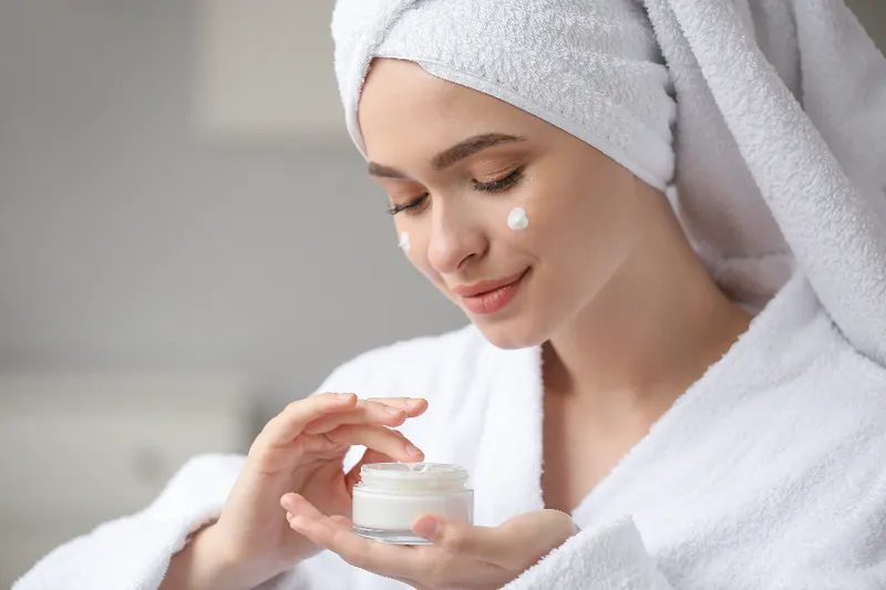 Donna in accappatoio applica una crema